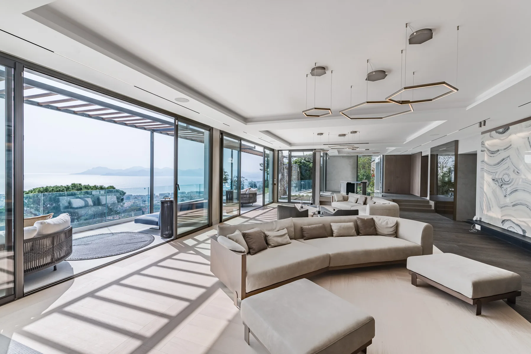 Grand salon avec sofa courbe et baies coulissantes face baie de Cannes