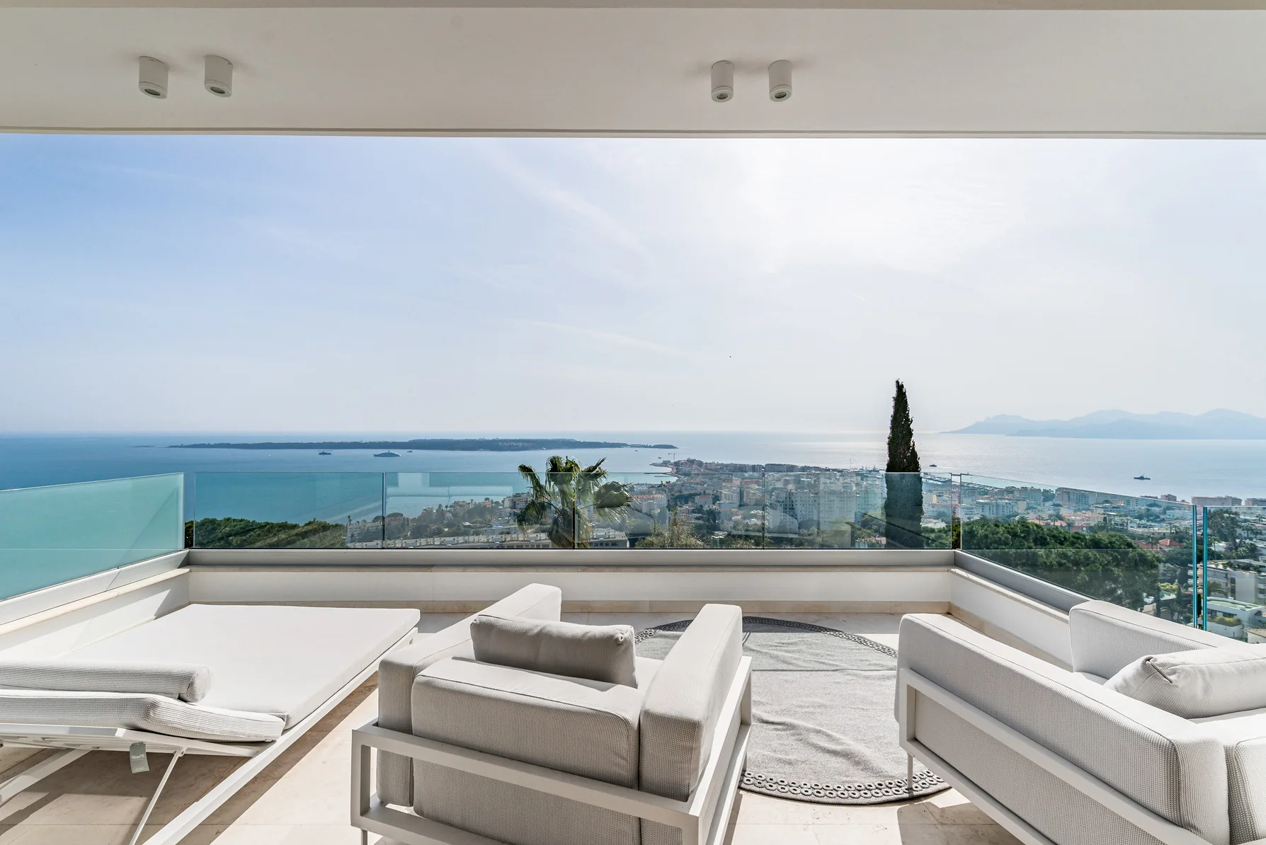 Grande terrasse face mer avec garde-corps verre et palmiers
