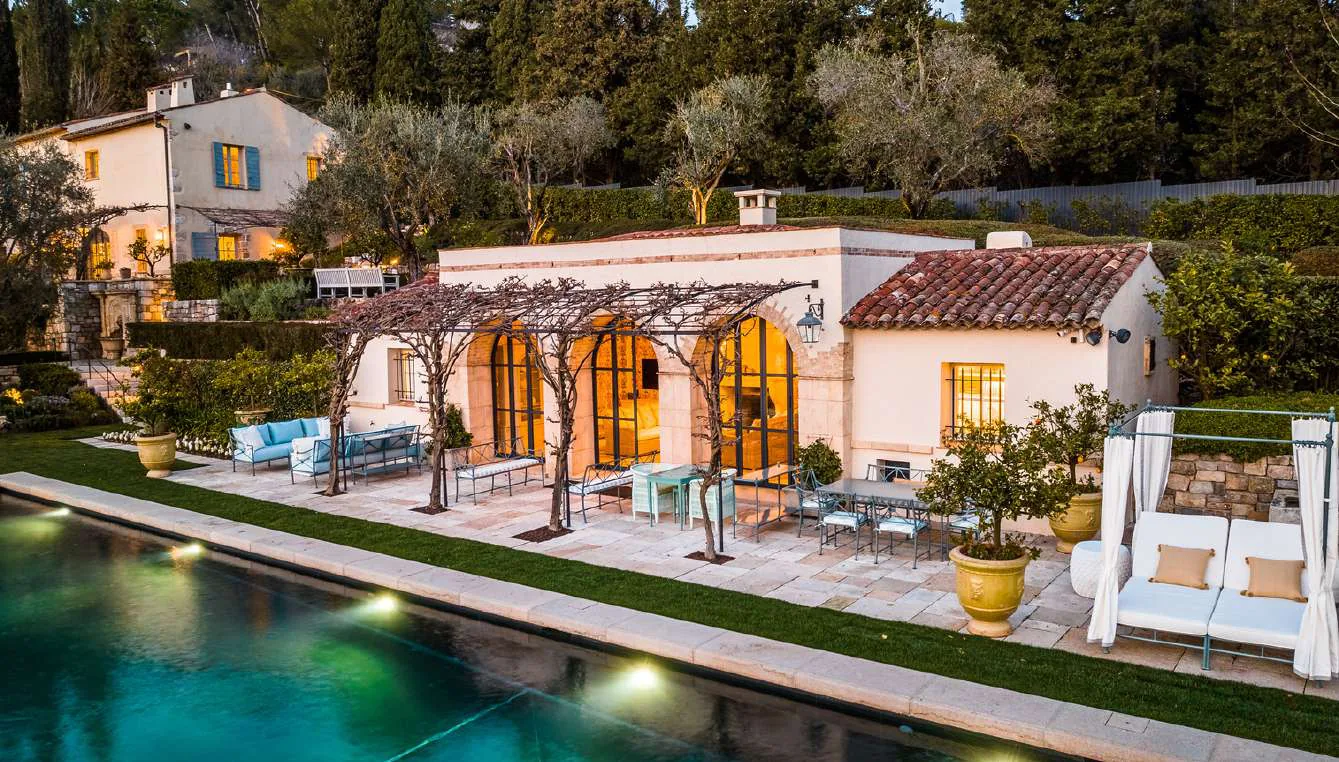 Pool house aux arches eclairees au crepuscule au bord de la piscine chauffee