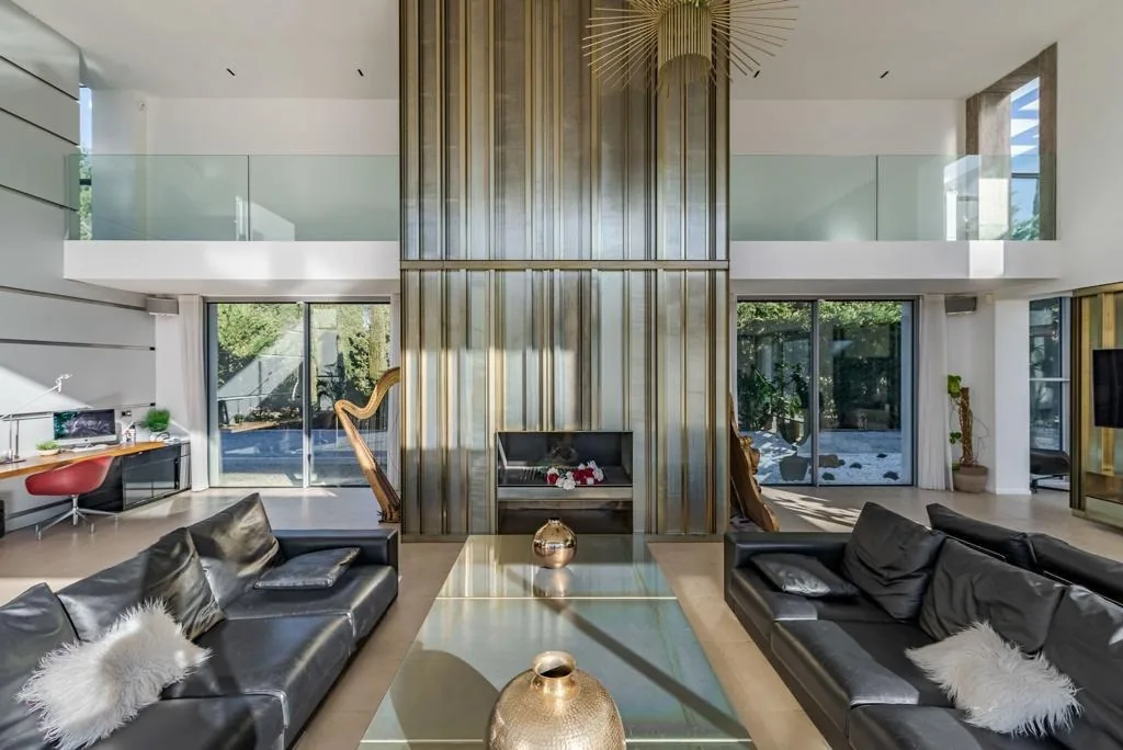 Salon double hauteur, cheminée laiton sculptural